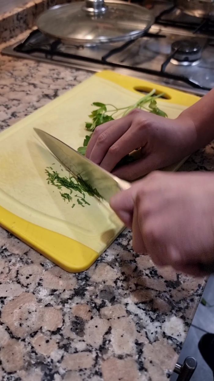 Agregar unas gotas de limón y cilantro, perejil y hierbabuena picados. Mezclar y apagar el fuego (207.28).