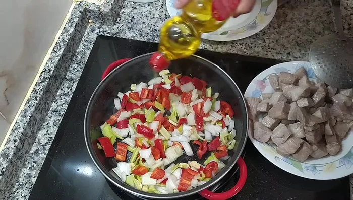Añadir las verduras (pimiento rojo, cebolla, puerro y ajos) a la cazuela y rehogarlas con un poco de sal.