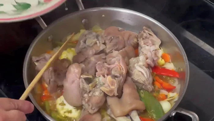 Incorporar las manitas de puerco, revolver y dejar hervir unos minutos más.