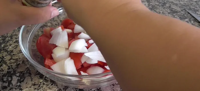 Añadir la albahaca y el pan cortado en trozos a la mezcla de tomates y cebolla.
