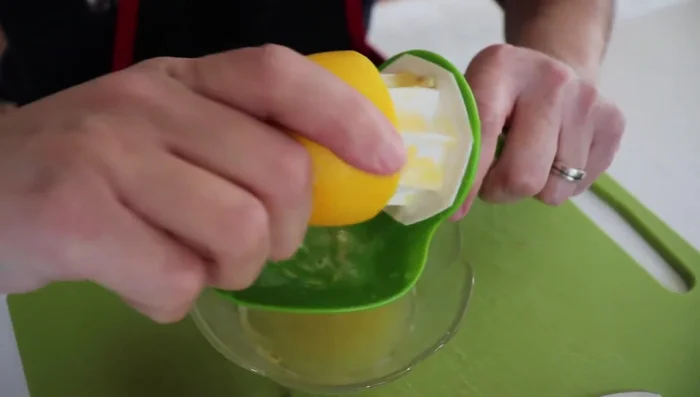 Exprimir el limón y agregar un poco de agua para cubrir la superficie de la olla a presión. Agregar el jugo de limón y los membrillos a la olla.