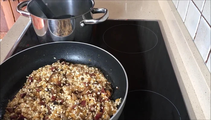 Agregar el caldo de verduras caliente poco a poco, removiendo constantemente, hasta que el arroz esté casi seco.