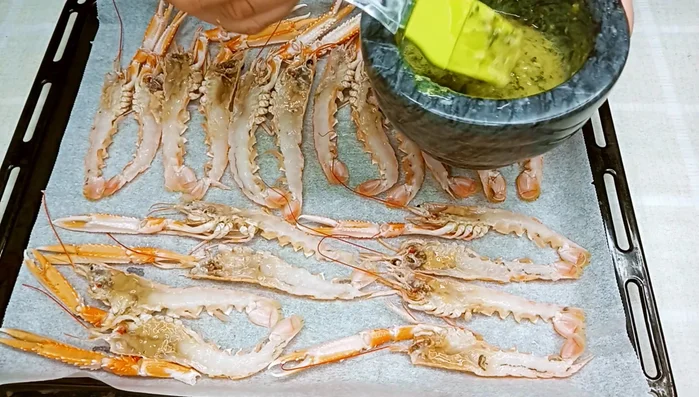 Untar las cigalas con el majado de ajo y perejil usando un pincel.