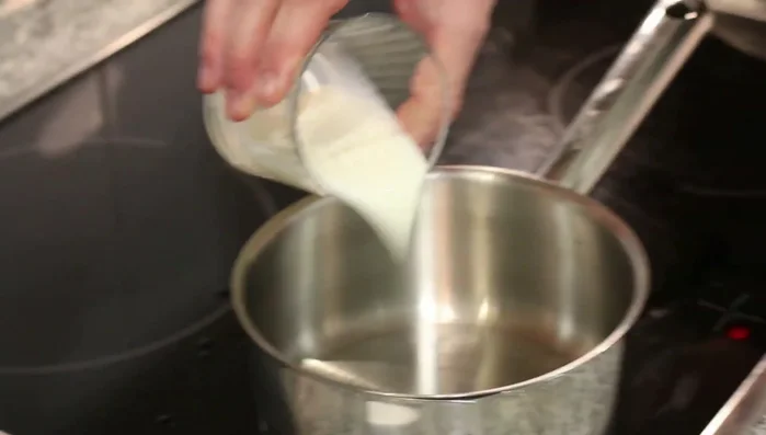 Añadir la leche al líquido rojo de pimentón en la sartén y llevar a ebullición.