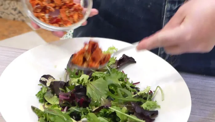 Añadir a la ensalada los tomates secos, la cebolla frita, el arroz salvaje, más vinagreta y mezclar.