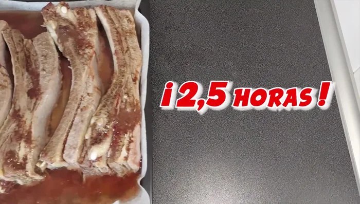 Sacar las costillas del horno después de 2 horas y media. Untar la parte superior con el majado, reservando una parte para la vuelta.