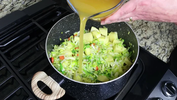 Agregar el caldo de verduras y la hoja de laurel. Llevar a ebullición, tapar y cocinar a fuego medio-bajo durante 15-20 minutos, o hasta que las papas estén cocidas.