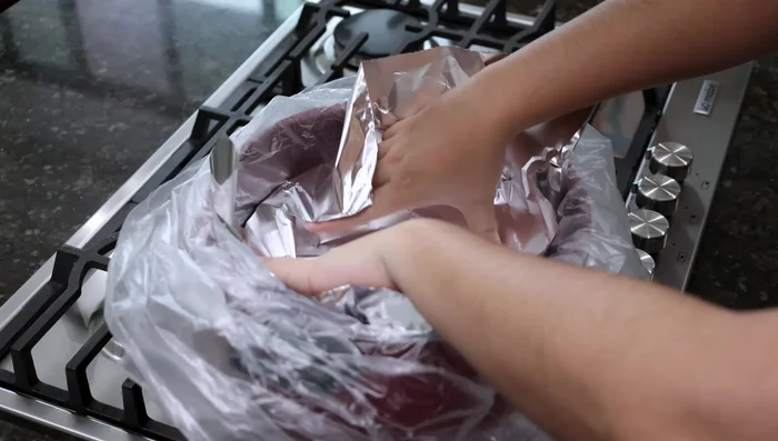 En la vaporera, colocar una bolsa plástica, papel aluminio y una capa de tortillas de maíz frías. Agregar los tacos rellenos, cebolla picada y salsa colada en capas.