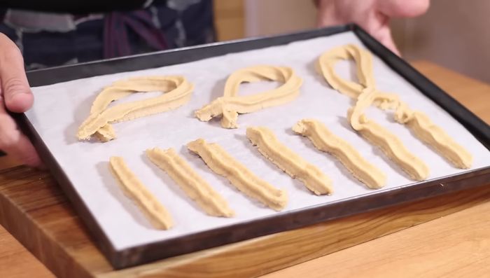 Rociar los churros con aceite en spray.