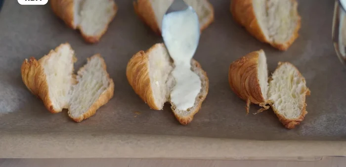 Colocar las lonchas de jamón y queso. Agregar más bechamel y tapar con la parte superior del croissant.