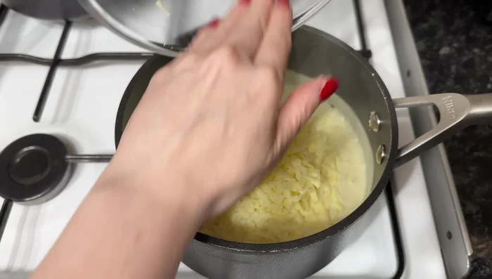 Retira del fuego y agrega el queso cheddar rallado, revolviendo hasta que se derrita.