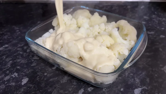 Coloca la coliflor en una sola capa en una fuente de horno. Vierte la salsa de queso por encima y agrega queso parmesano rallado (opcional).