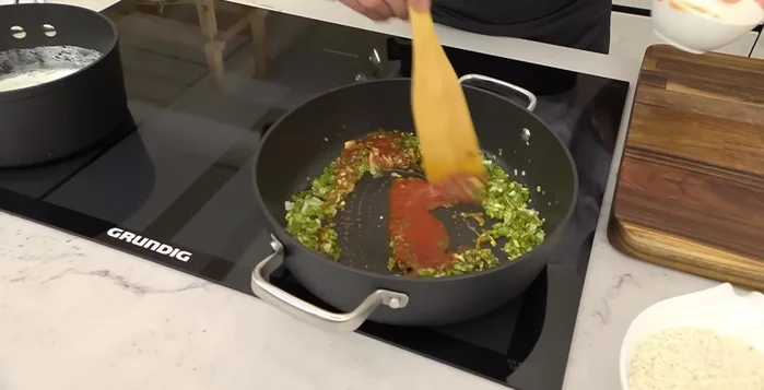 Agregar el tomate triturado y cocinarlo un poco.