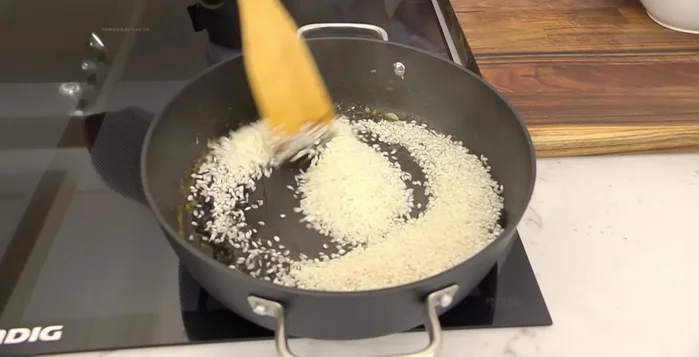 Agregar el arroz al sofrito con la tinta y sofreírlo ligeramente.