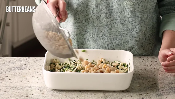 Agregar los frijoles mantequilla escurridos y enjuagados (o cualquier otro tipo de frijol). Extender sobre la mezcla de tofu. [113.119]