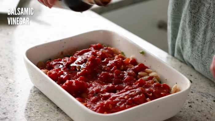 Agregar unas gotas de vinagre balsámico. Si la salsa no tiene suficiente sal, agregar más. Añadir hojuelas de pimienta o pimienta negra al gusto. [130.84]