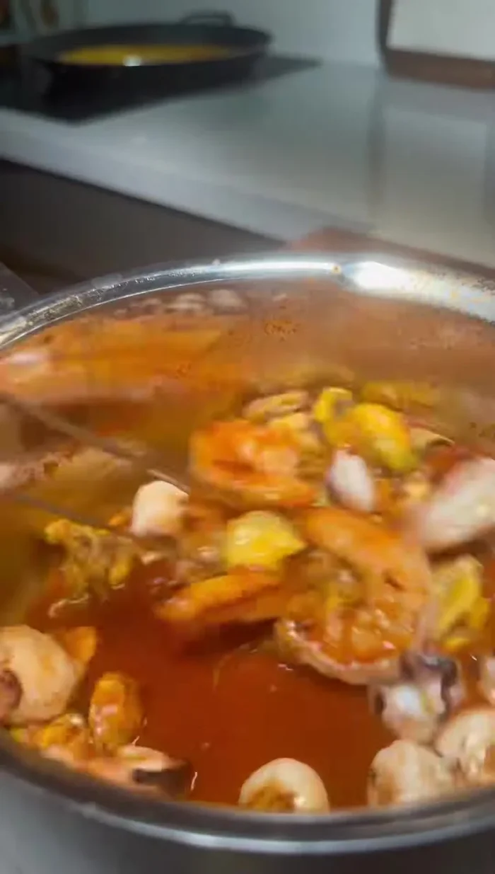 Añadir las gambas y los mejillones pelados a la paella. Agregar el jugo reservado de los mejillones.