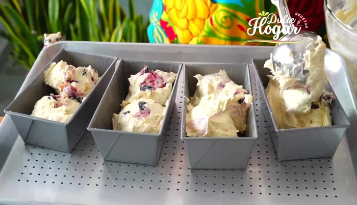 Rellenar los moldes con la masa hasta 3/4 de su capacidad, decorar con arándanos y cobertura.