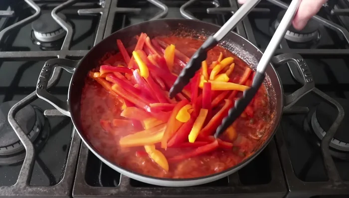 Añadimos los pimientos morrones dulces cortados gruesos a la salsa. Desmenuzamos la panceta y la añadimos junto con el pollo (con la piel hacia arriba).