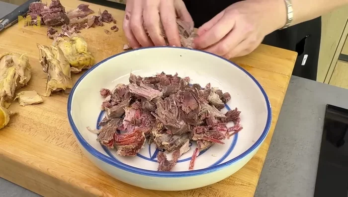 Limpiar la carne del cocido, quitando huesos y pieles. Desmigar la carne con los dedos.
