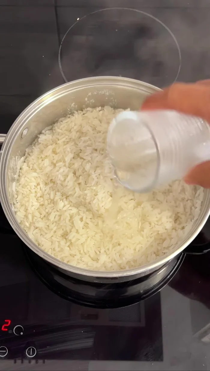 Si el arroz está muy seco, agregar un poco de agua para humedecerlo. Para chaufa, solo agua; para arroz blanco, se puede agregar agua con ajos confitados.