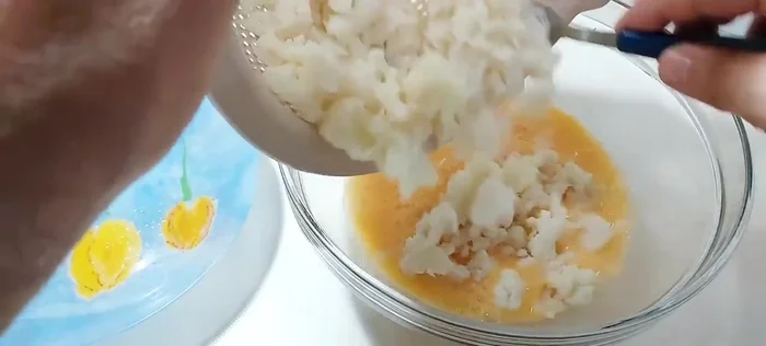 Añadir la coliflor escurrida y la cebolla sofreída a los huevos batidos. Mezclar bien.