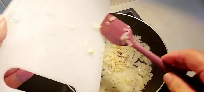 Añadir dos dientes de ajo picados a la cebolla y cocinar hasta que estén dorados.