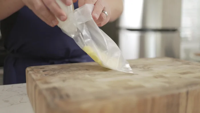 Sazonar las papas con sal. Colocar en una bolsa criovac con grasa de pato derretida y la bolsita de hierbas. Sellar la bolsa.
