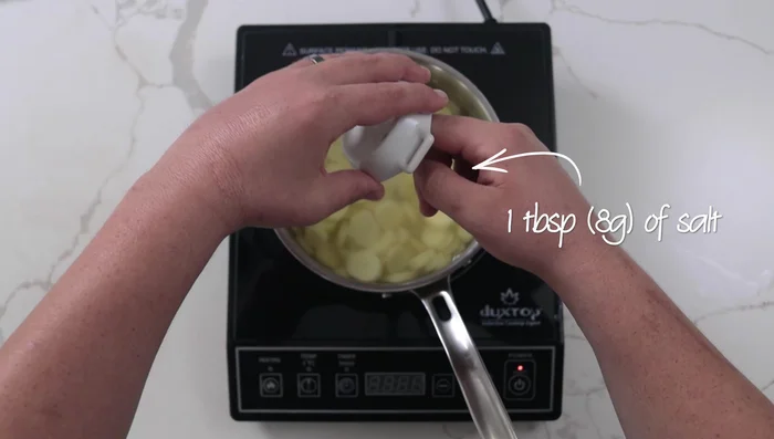 Cocer las papas en agua con sal a fuego medio-bajo (30-35 minutos) hasta que estén tiernas. Reducir crema en una olla aparte en un 33%.