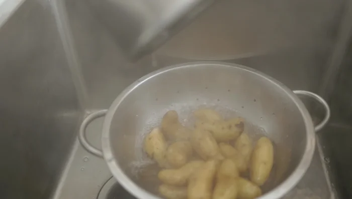 Escurrir las papas, pelarlas calientes. Agregar un chorrito de agua en la olla para evitar que se forme una película. Machacar las papas en la olla.