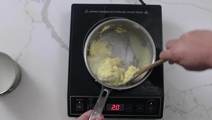 Calentar leche a fuego lento. Agregar al puré hasta que quede suave, mezclando con una cuchara de madera. Agregar la mantequilla fría en cubos gradualmente para formar una emulsión.