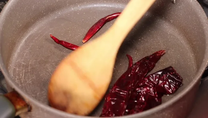 Agregar los jitomates y continuar sofriendo. Una vez listos, agregar todo a la licuadora junto con el cilantro, las pimientas gordas, el comino y el chile de árbol (al gusto). Licuar perfectamente.