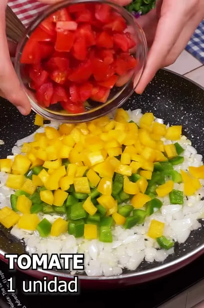 Agregar medio pimiento verde, medio pimiento amarillo y un tomate picado al sofrito. Sofreír todo junto.