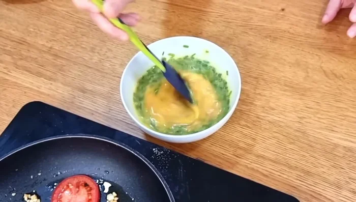 Añadir la mezcla de huevo y atún a la sartén con los tomates.