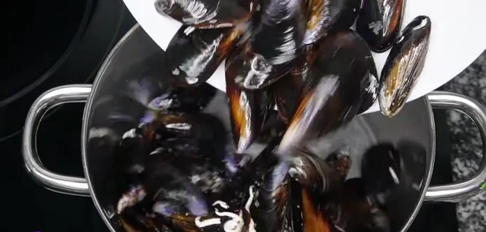 Escurrir los mejillones y cocinarlos en una cazuela honda con 100 ml de agua, 100 ml de vino blanco, una rodaja de limón, 2 hojas de laurel partidas, una pizca de sal. Cocinar a fuego medio-alto con la tapa puesta hasta que se abra el líquido (unos 4 minutos). Retirar los mejillones abiertos y desechar los que queden cerrados.