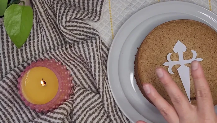 Decorar la tarta con azúcar glas en forma de cruz de Santiago.