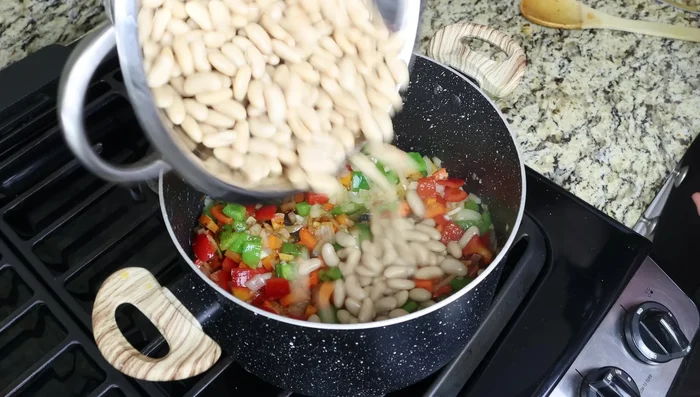 Incorporar los frijoles blancos y el caldo de verduras. Agregar una hoja de laurel.