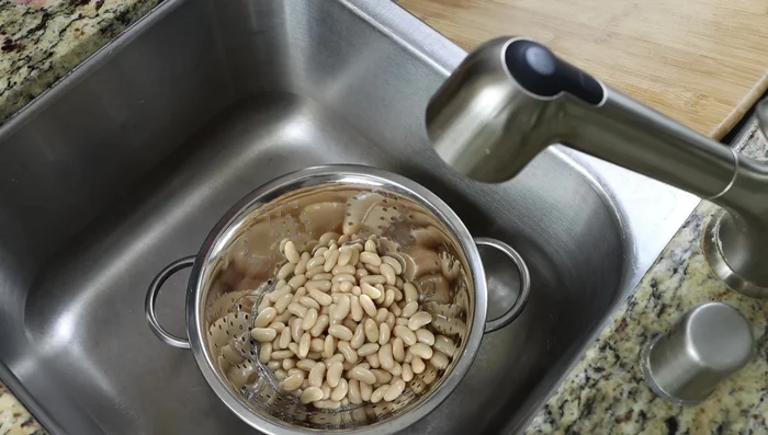 Escurrir y enjuagar dos latas de frijoles blancos.