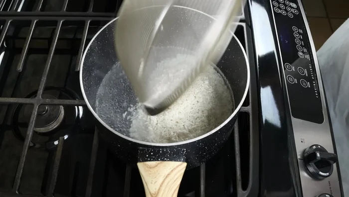 Una vez que el agua hierva, agregar el arroz a la cacerola, mezclar suavemente, bajar el fuego y cocinar a fuego lento durante 15-18 minutos hasta que se absorba toda el agua.
