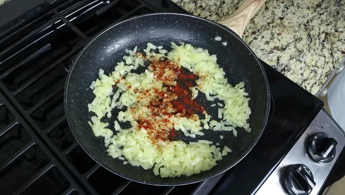 Añadir pimentón, jengibre, cúrcuma, canela, azafrán, cilantro, sal y pimienta a la sartén. Mezclar bien.