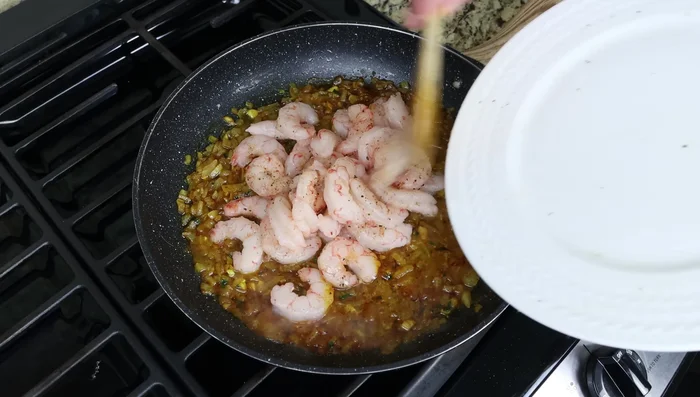 Agregar los camarones a la sartén, mezclar suavemente y cocinar a fuego medio-bajo con la tapa puesta durante 3-4 minutos hasta que estén cocidos.