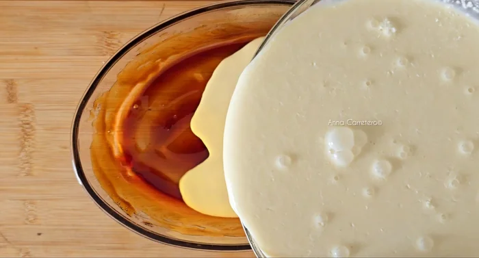 Vierte la mezcla sobre el caramelo y el coco rallado en el molde.