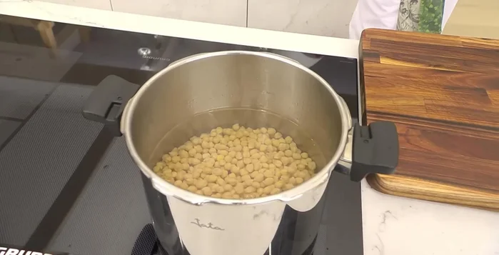Cocer los garbanzos en agua hirviendo con una hoja de laurel, un puerro troceado y una cebolla entera. Agregar sal. Cocer durante aproximadamente 20 minutos, o hasta que estén tiernos. (160.2)