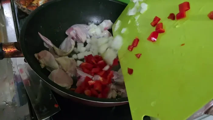 Agregar la cebolla y el morrón al pollo sofrito.
