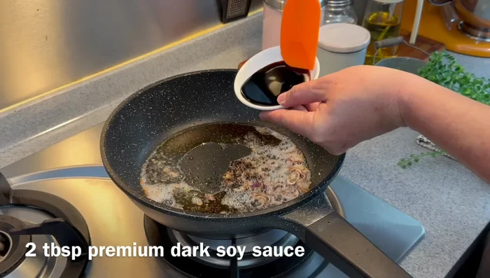 Agregar los ingredientes de la salsa: Agregar agua, salsa de soja clara, salsa de soja oscura y azúcar a la sartén. Mezclar. (269.72)
