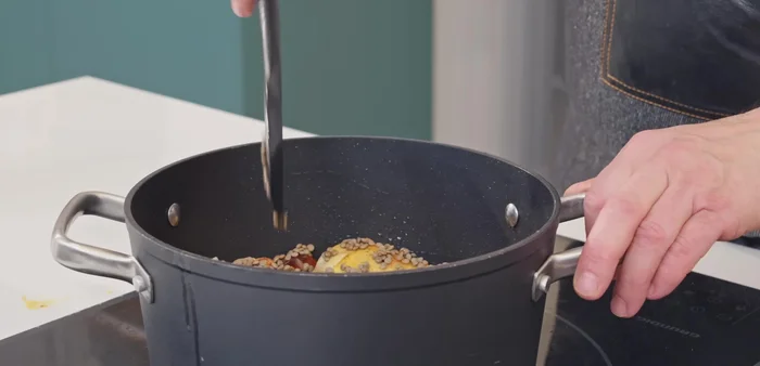 Incorporar las lentejas, cubrir con agua, agregar la crema de tomate triturada, la hoja de laurel y la pastilla de caldo de pollo. Remover bien.