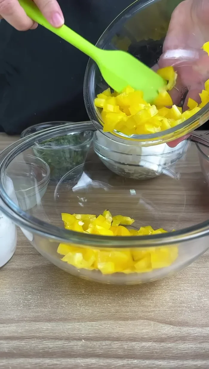 En otro tazón, preparar el aderezo: agregar pimiento amarillo picado, pimiento rojo picado, cebolla picada y perejil picado.