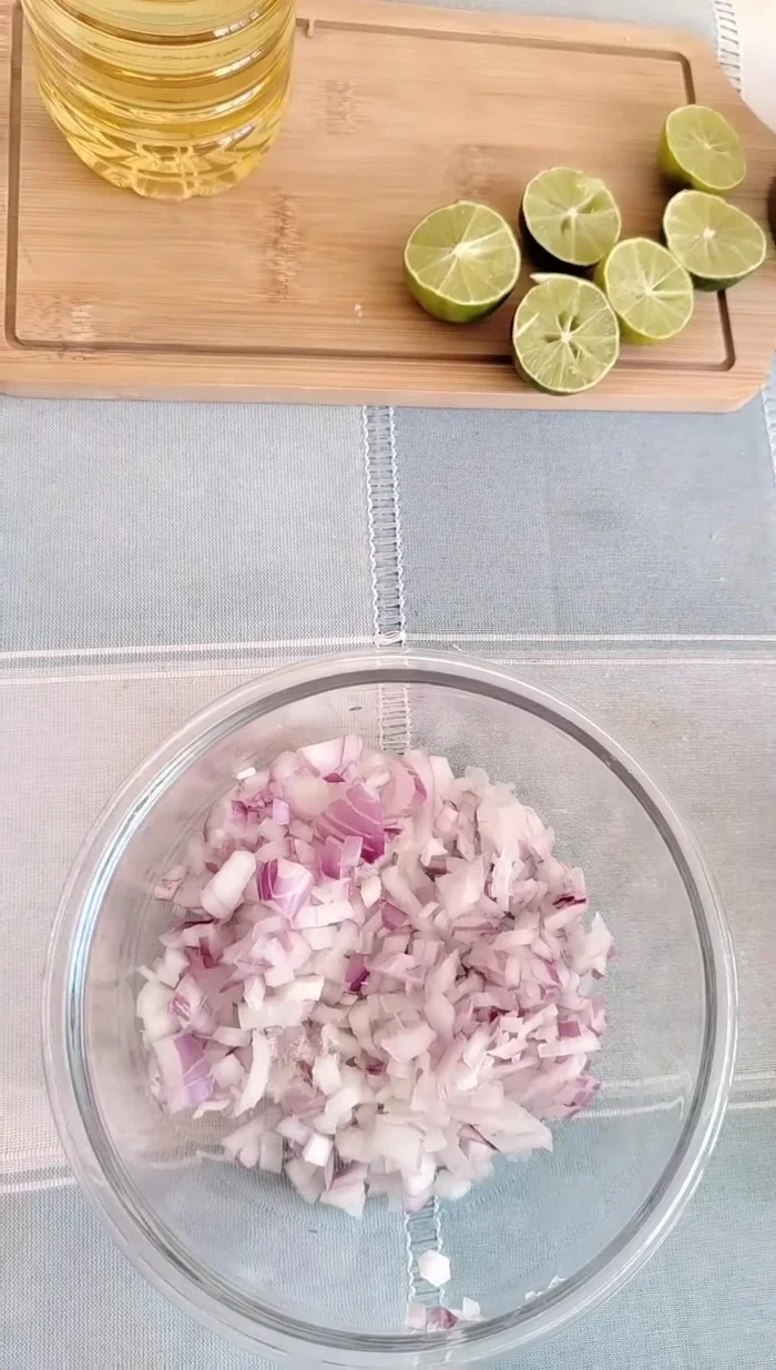 Preparar el ceviche de atún: Agregar sazonador, cebolla picada, sal y limón exprimido a la cebolla. Mezclar bien.
