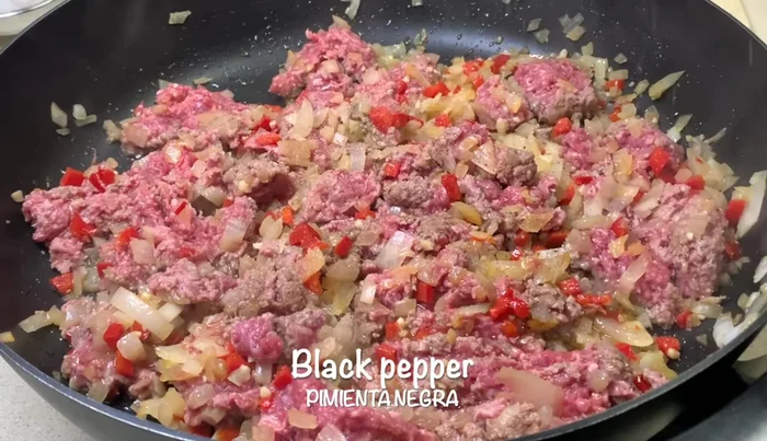 Agregar sal, pimienta, comino, orégano y pimentón. Mezclar y cocinar por 3 minutos, machacando para romper los grumos.