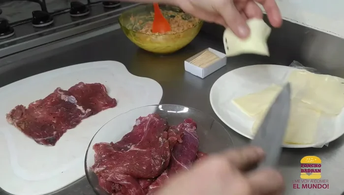 Armar los rollos: colocar sobre cada milanesa de carne, media lámina de queso mozzarella, el relleno y enrollar. Asegurar con palillos. [215.7]
